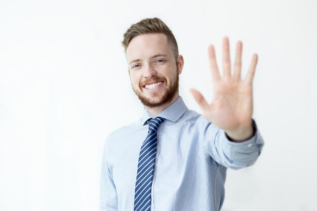 Hombre de negocios sonriente que muestra el gesto de la parada