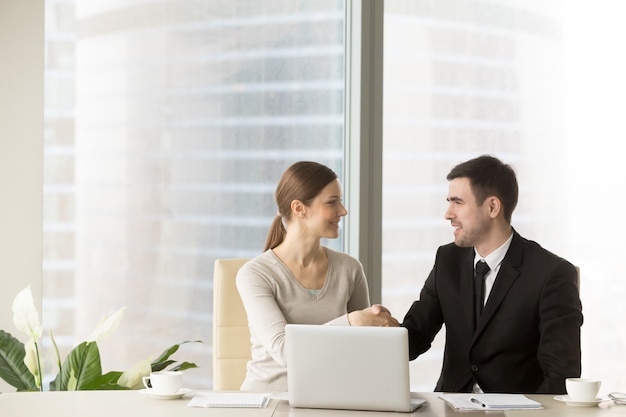 Hombre de negocios sonriente que sacude las manos con la empresaria