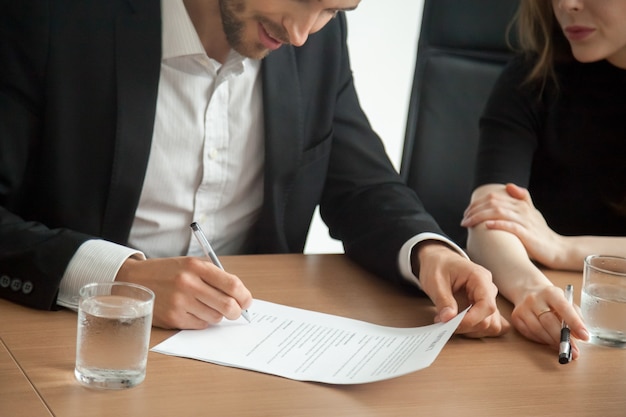 Hombre de negocios sonriente satisfecho en contrato de firma del traje en el concepto de la reunión