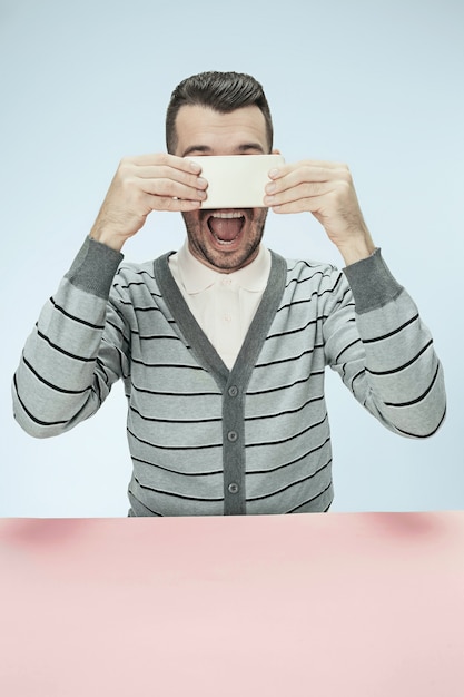 Foto gratuita hombre de negocios sorprendido hablando por teléfono sentado en la mesa.