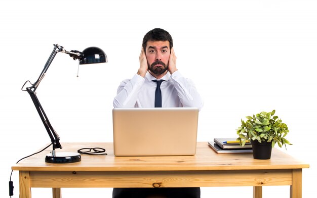 Hombre de negocios en su oficina cubriendo sus oídos