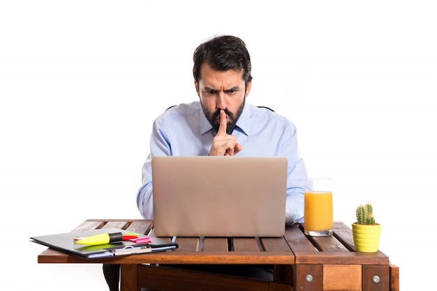 Hombre de negocios en su oficina haciendo gesto de silencio