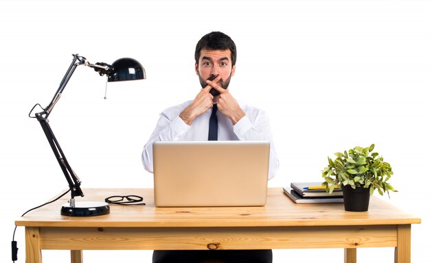 Hombre de negocios en su oficina haciendo gesto de silencio