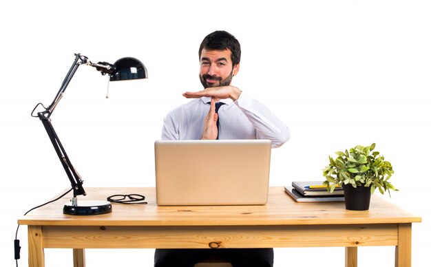 Hombre de negocios en su oficina haciendo gesto del tiempo hacia fuera