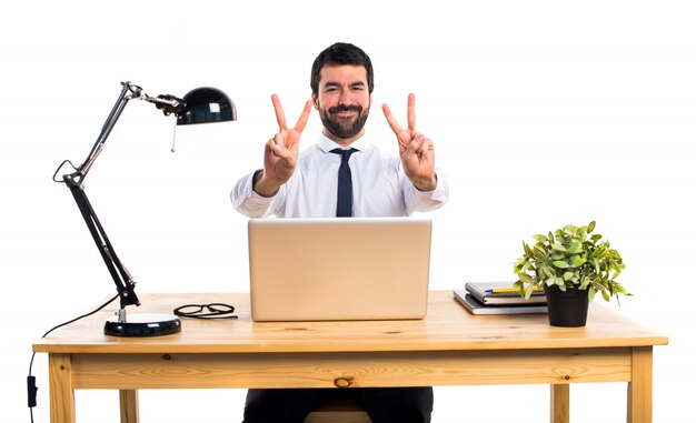 Hombre de negocios en su oficina haciendo gesto de victoria