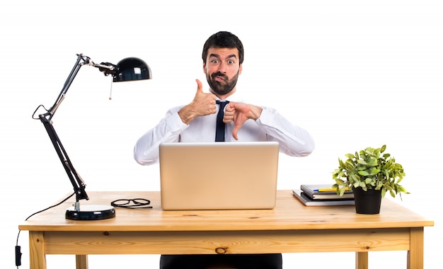 Hombre de negocios en su oficina haciendo signo bueno-malo