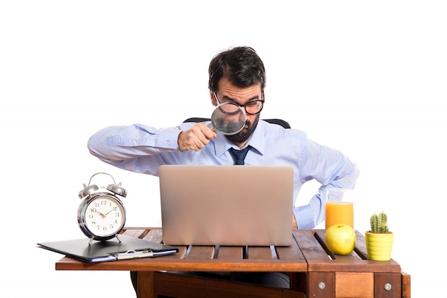 Foto gratuita hombre de negocios en su oficina con lupa