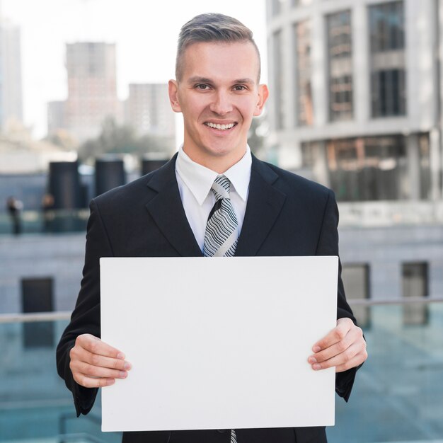 Hombre de negocios sujetando plantilla de papel en blanco
