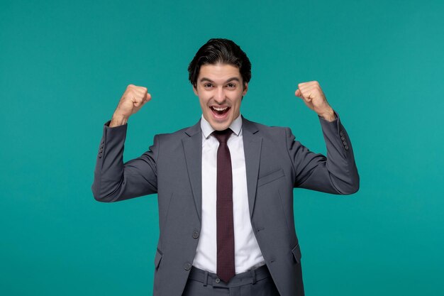 Hombre de negocios súper emocionado guapo lindo morena chico en traje de oficina gris y corbata levantando los puños