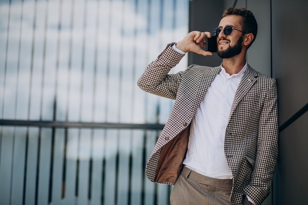 Foto gratuita hombre de negocios con teléfono fuera del centro de la oficina