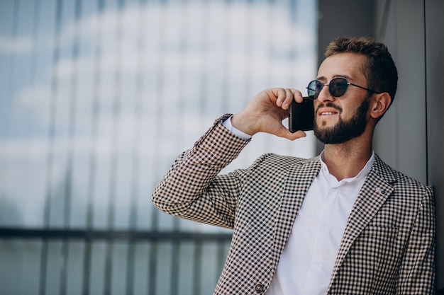 Foto gratuita hombre de negocios con teléfono fuera del centro de la oficina