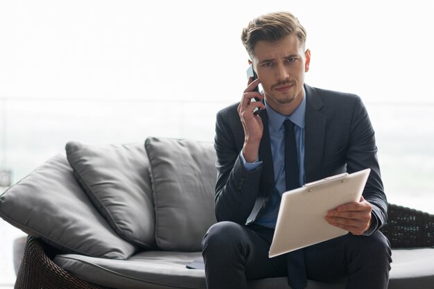 El hombre de negocios tensa llamada en el teléfono en el sofá