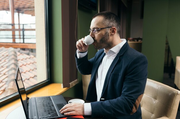 Hombre de negocios tomando café y mirando portátil