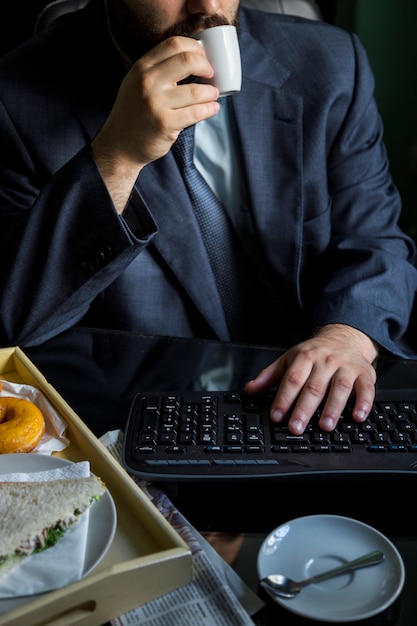 Hombre de negocios tomando café con el teclado en el escritorio