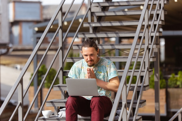 Hombre de negocios trabajando al aire libre con laptop, mirando en la pantalla de la computadora
