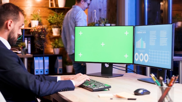 Hombre de negocios trabajando en una computadora con monitor verde. Empleado de oficina