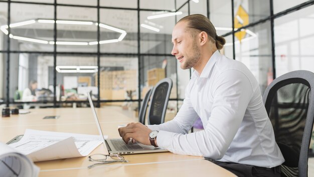 Hombre de negocios trabajando con portátil en oficina