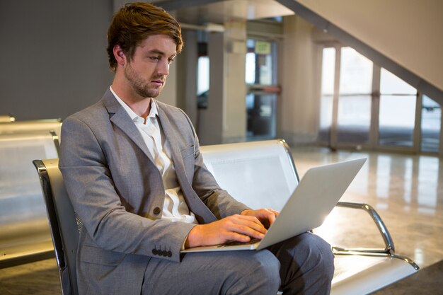 Hombre de negocios trabajando en su computadora portátil en la sala de espera