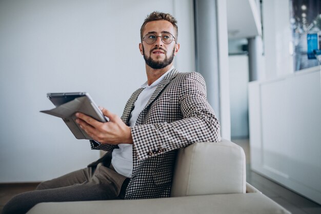 Hombre de negocios trabajando en tableta y sentado en el sofá