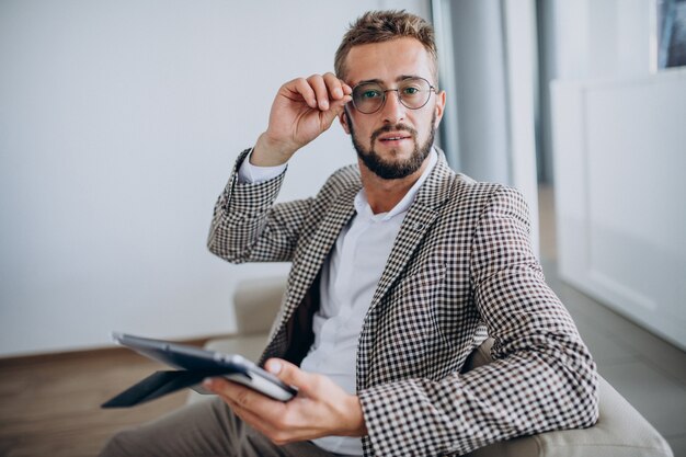 Hombre de negocios trabajando en tableta y sentado en el sofá