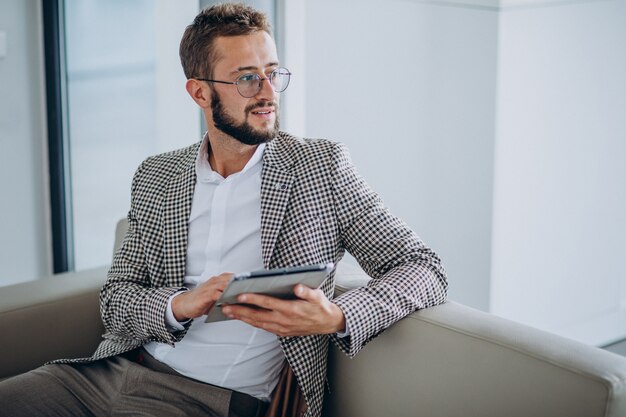 Hombre de negocios trabajando en tableta y sentado en el sofá