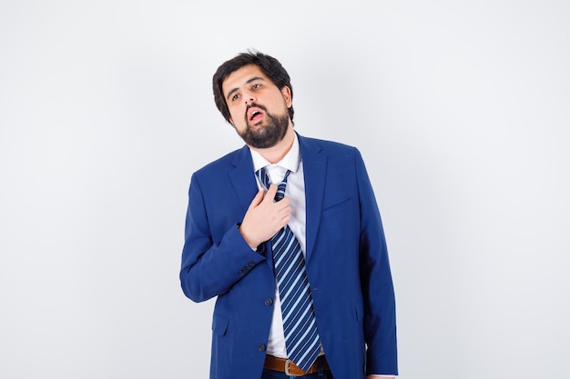 Hombre de negocios en traje formal tratando de quitarse la corbata y con aspecto cansado, vista frontal.