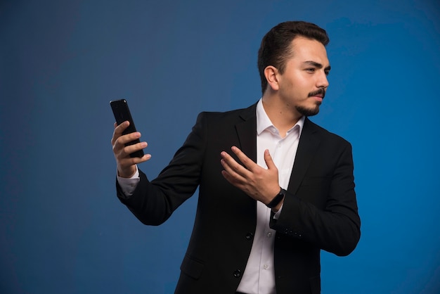 Foto gratuita hombre de negocios en traje negro comprobando su teléfono.