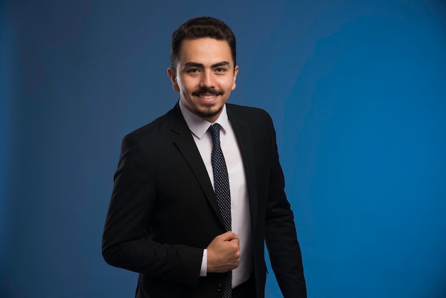 Hombre de negocios en traje negro con corbata posando.