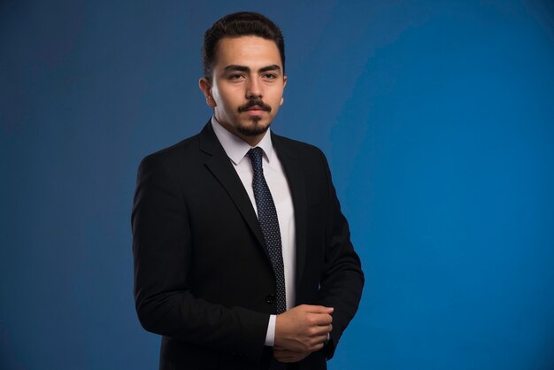 Hombre de negocios en traje negro con corbata posando.