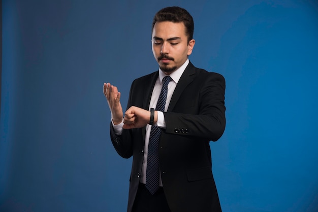 Hombre de negocios en traje negro esperando a alguien y molesto.