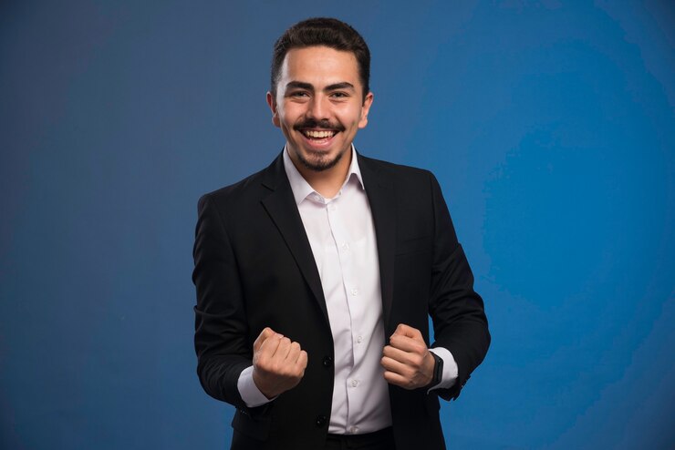 Foto gratuito hombre de negocios en traje negro hace signo de suerte.