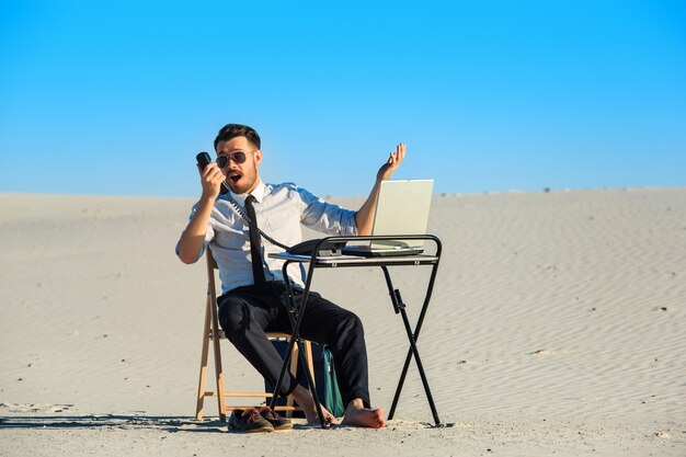Hombre de negocios usando la computadora portátil en un desierto