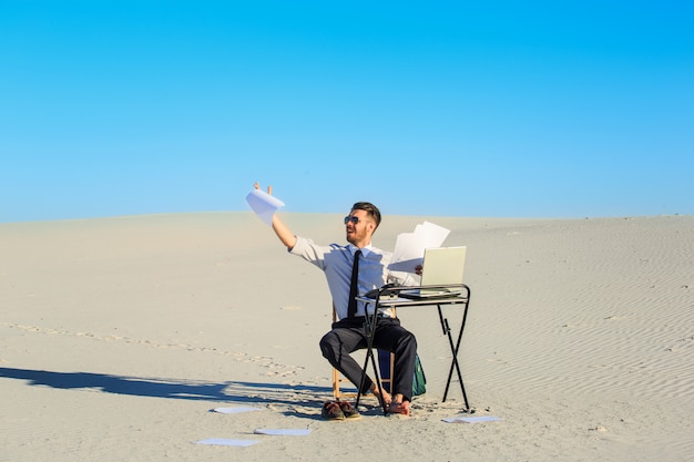 Hombre de negocios usando la computadora portátil en un desierto