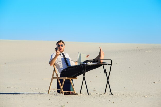 Hombre de negocios usando la computadora portátil en un desierto