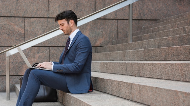 Foto gratuita hombre de negocios usando la computadora portátil en pasos