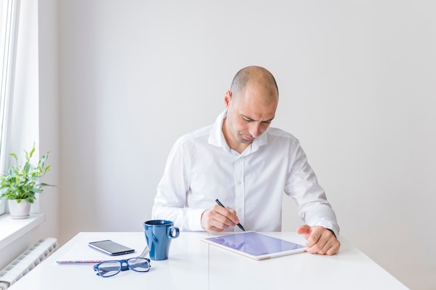 Foto gratuita hombre de negocios usando tableta digital gráfica en el lugar de trabajo