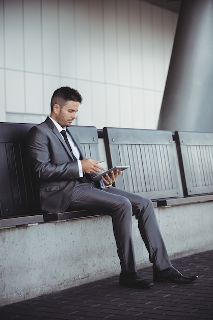Hombre de negocios usando tableta digital mientras está sentado en un banco