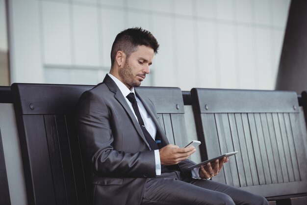 Hombre de negocios usando tableta digital y teléfono móvil