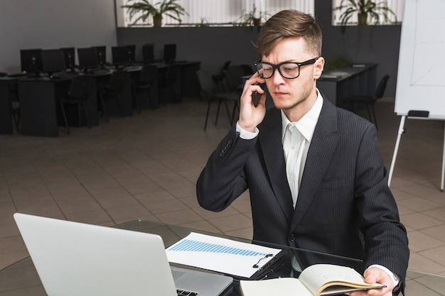 Foto gratuita hombre de negocios usando el teléfono celular en la oficina