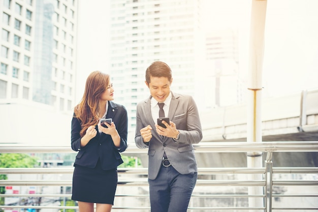 Hombre de negocios usando el teléfono con colega fuera.