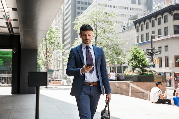 Hombre de negocios usando teléfono inteligente en la calle