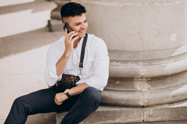 Hombre de negocios usando el teléfono por la universidad