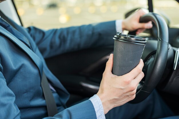 Hombre de negocios con vaso de café en coche