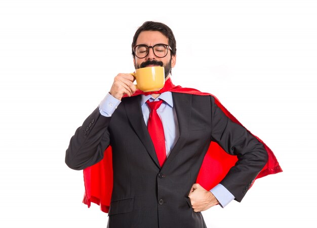 Hombre de negocios vestido como superhéroe bebiendo café