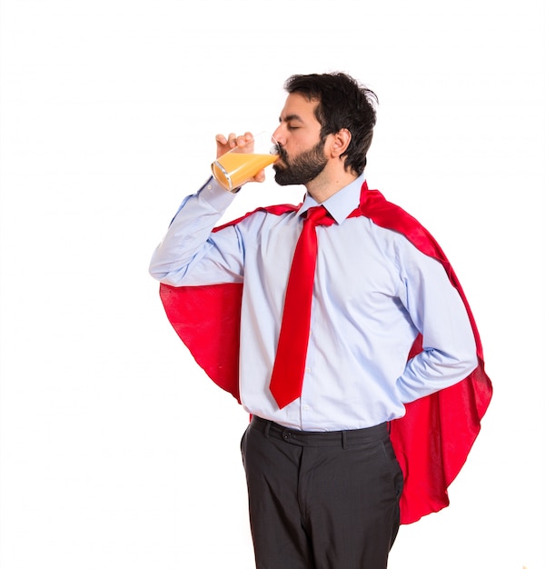 Hombre de negocios vestido como superhéroe bebiendo jugo de naranja