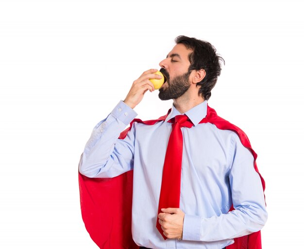 Hombre de negocios vestido como superhéroe comiendo una manzana