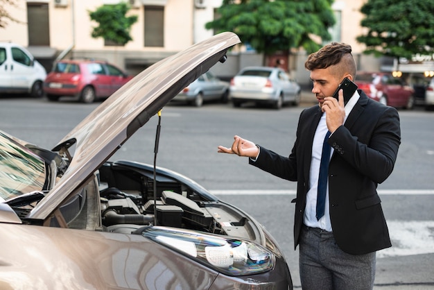 Hombre de negocios de vista lateral hablando con el servicio de coche