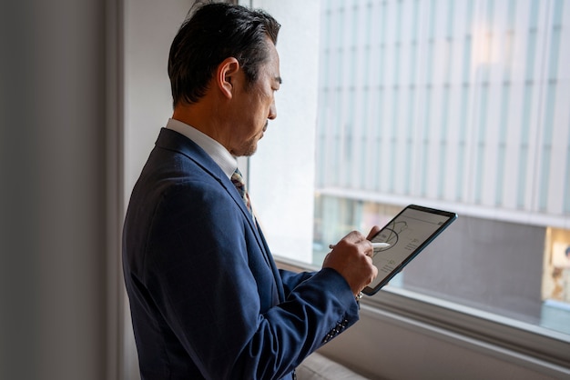 Foto gratuita hombre de negocios de vista lateral trabajando en ipad