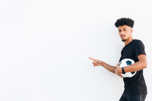 Hombre negro con balón de fútbol apuntando con el dedo