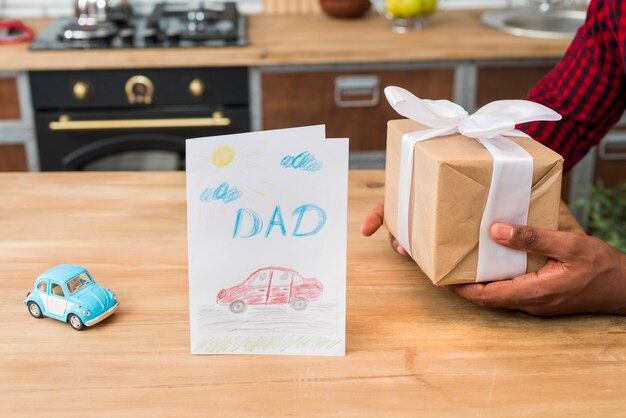 Hombre negro con caja de regalo cerca de tarjeta de felicitación